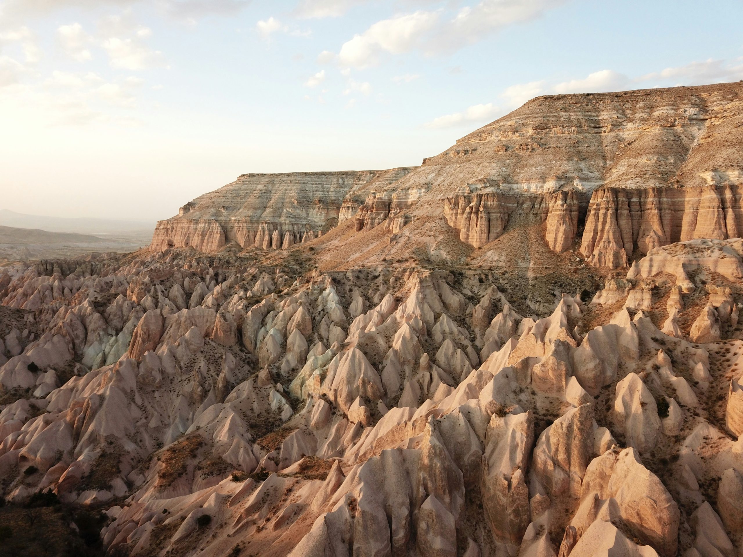 Eroded volcanic ridges and cone-shaped rock formations spreading below a flat-topped mesa in Cappadocia.