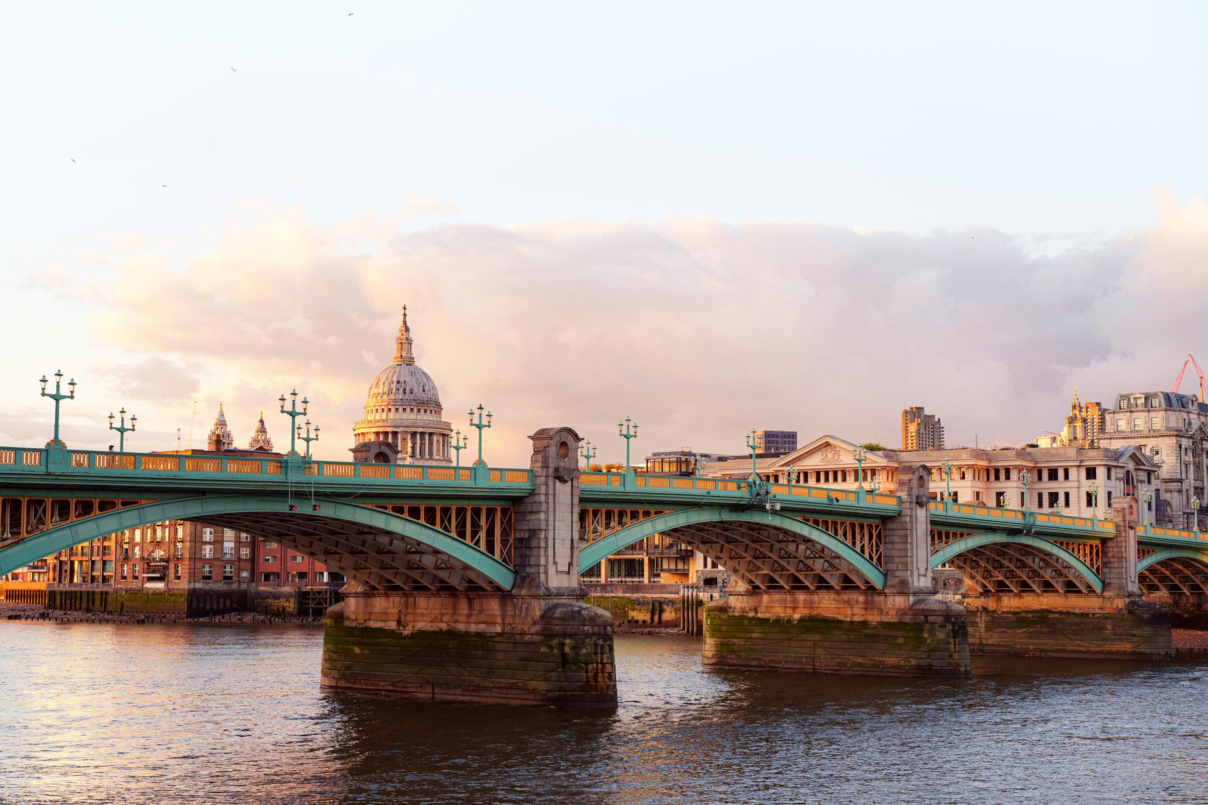 The dome of St Paul's Cathedral above Southwark Bridge, the Thames lit at sunset