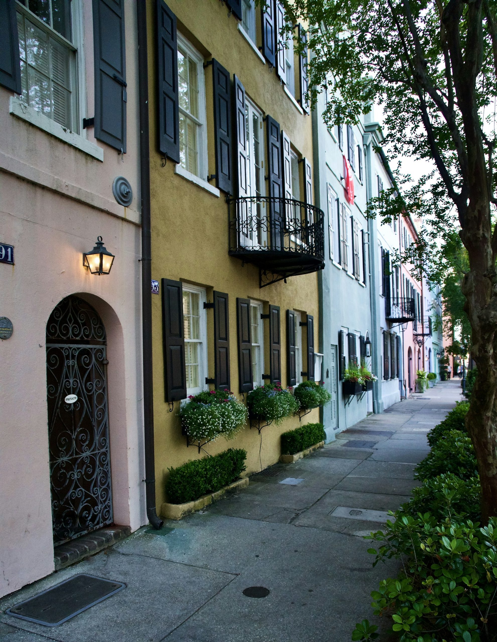 A lamp-lit street of pastel houses in historic Charleston.