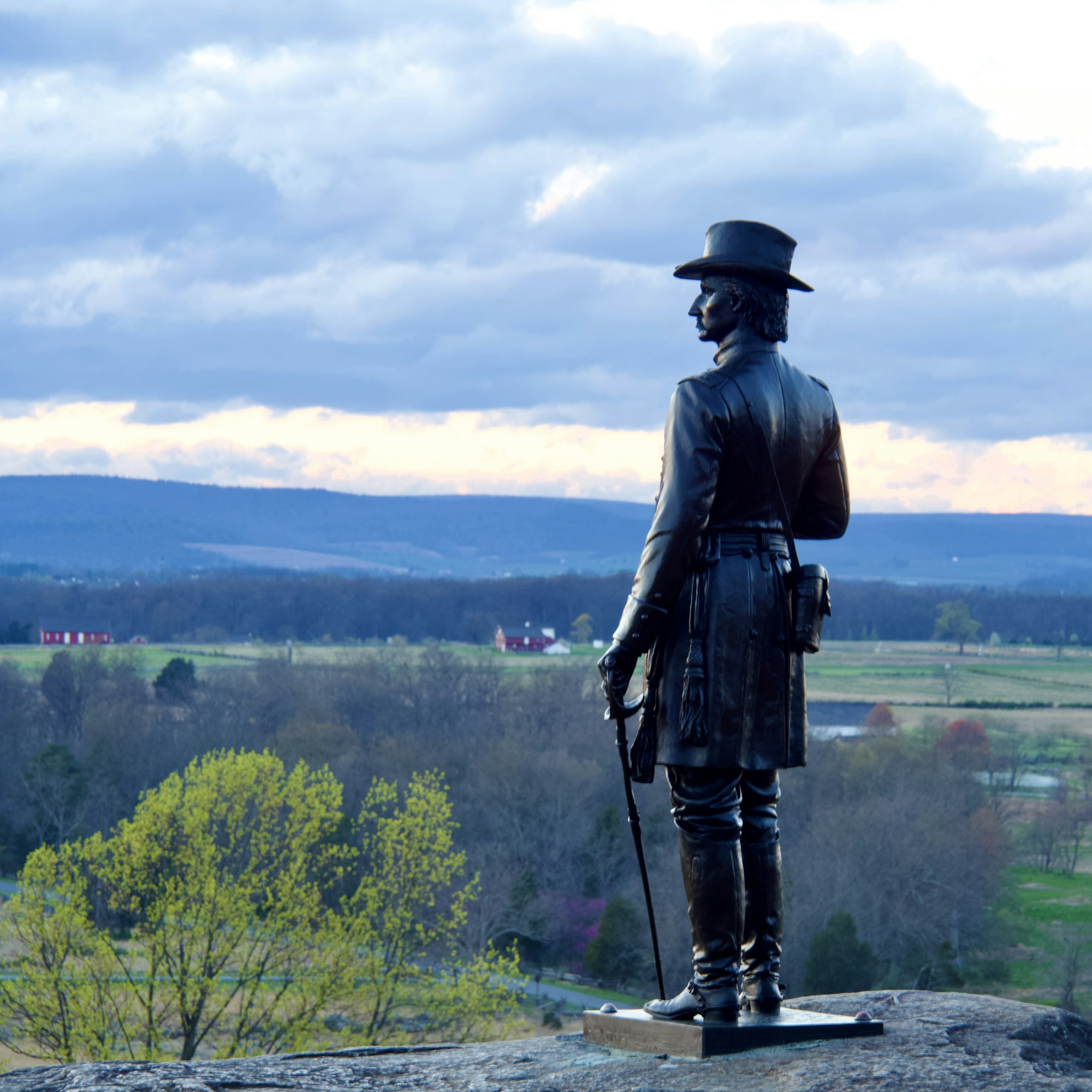 A soldier's figure on a monument looking out over the Gettysburg battlefield.