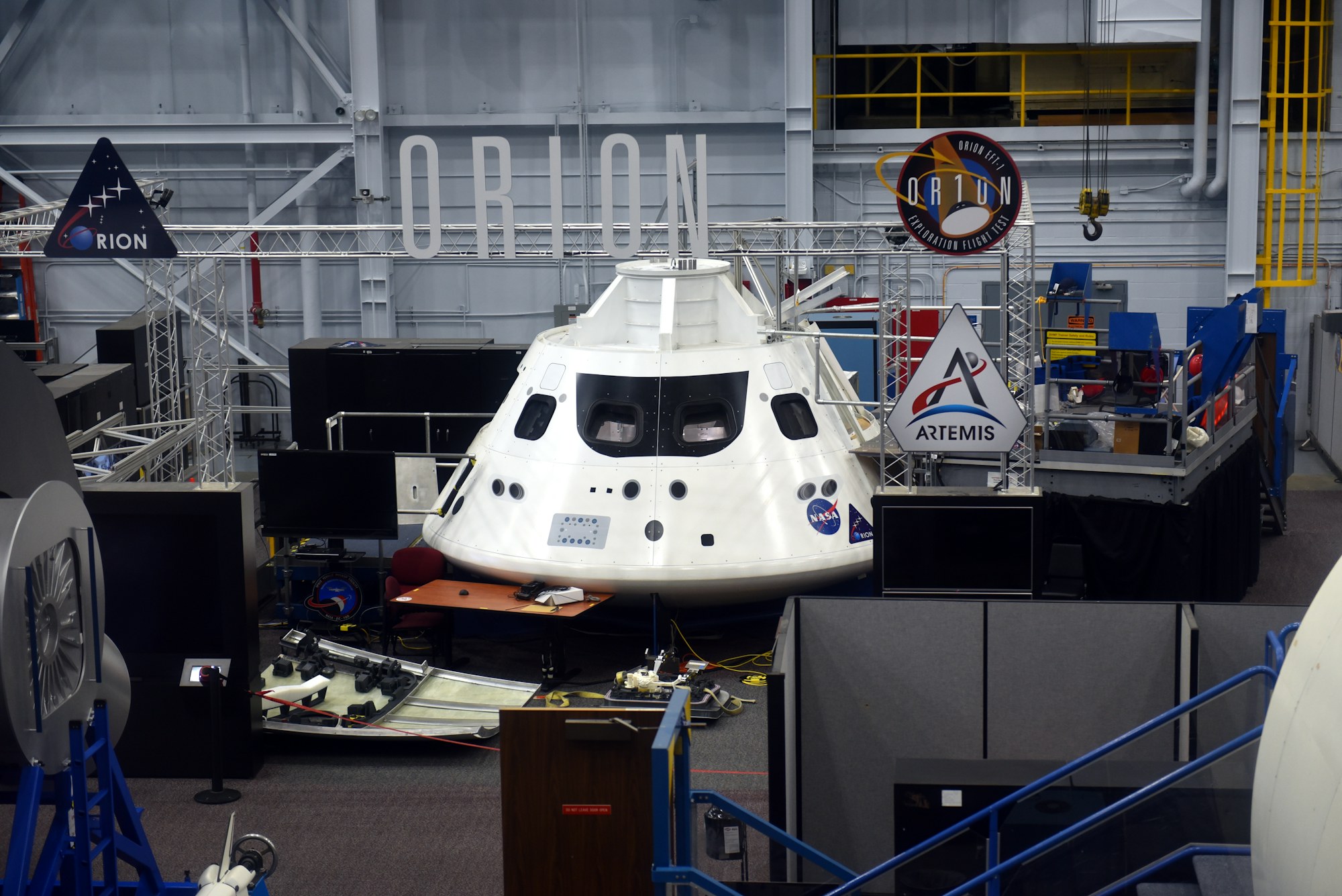 A spacecraft on display inside a hangar at Space Center Houston.