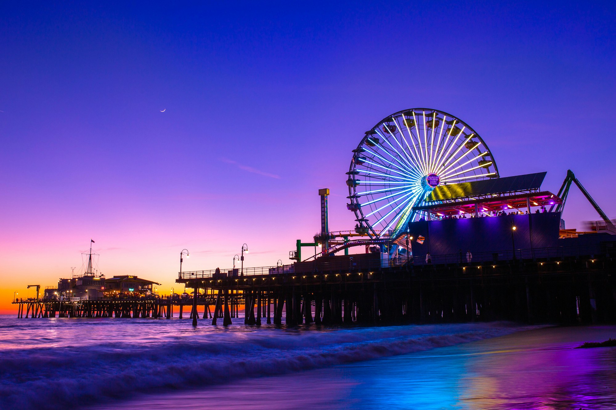 The Santa Monica Pier and Pacific Park Ferris wheel at dusk.