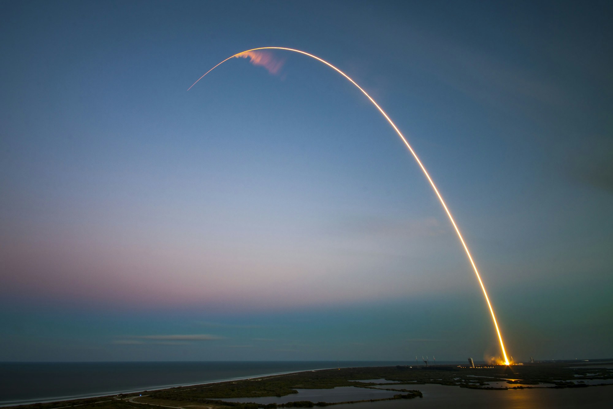 A launch trail rising from Cape Canaveral at dusk.