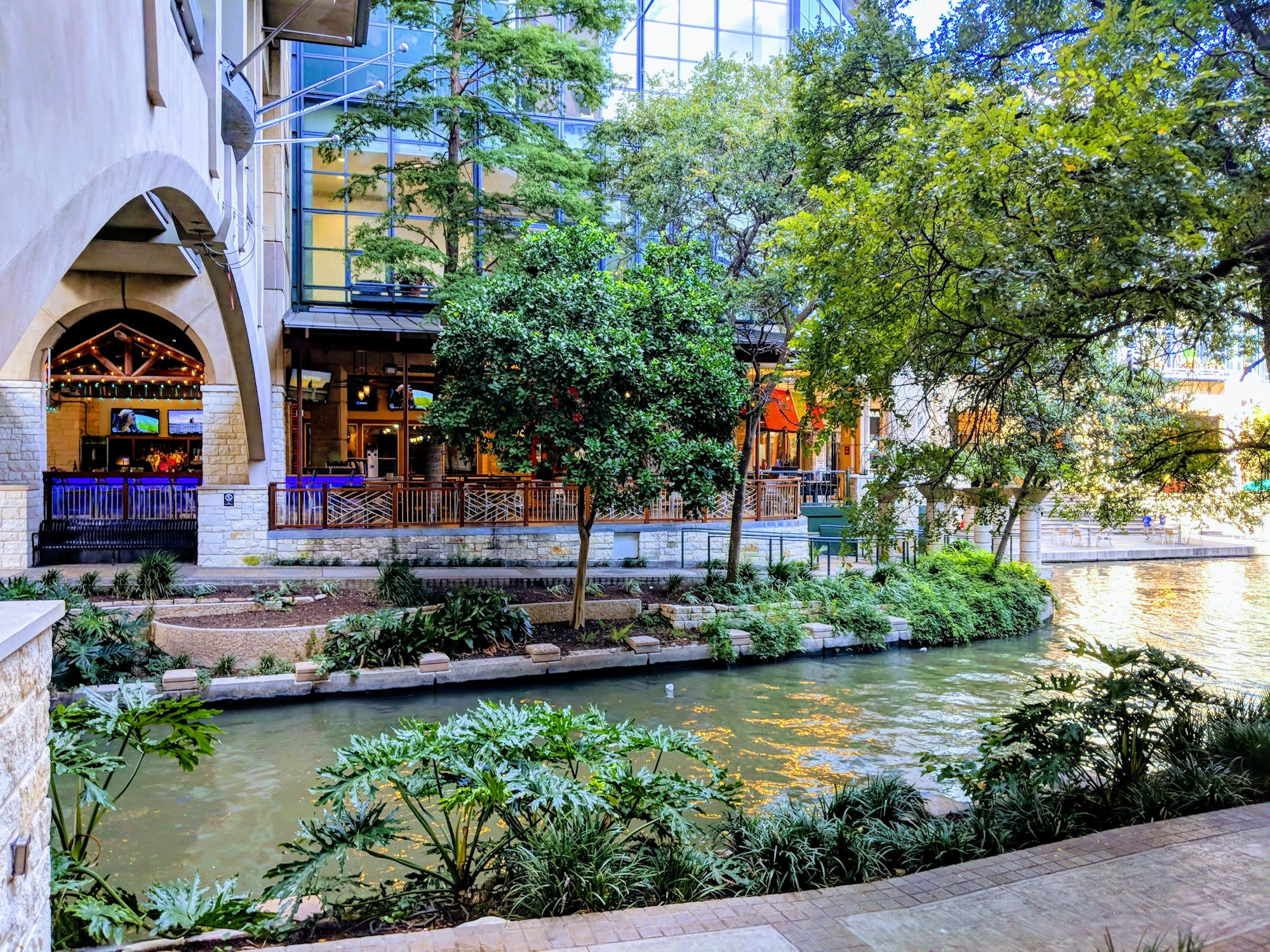 The San Antonio River Walk running between cafes and trees.
