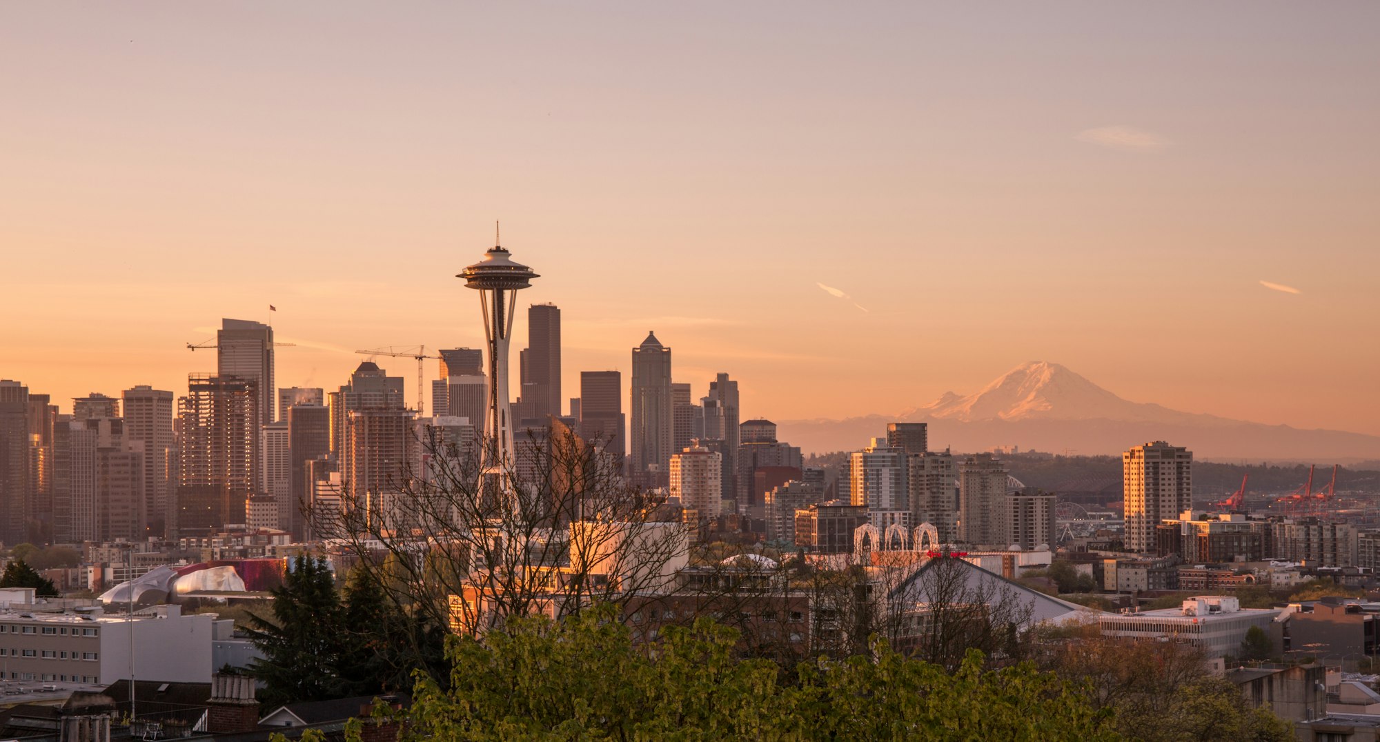 The Space Needle and Seattle skyline at sunset with Mount Rainier behind.