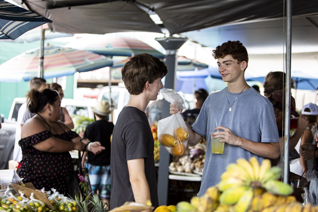 Two high school students volunteering at a local market during a community service abroad program in Hawaii.