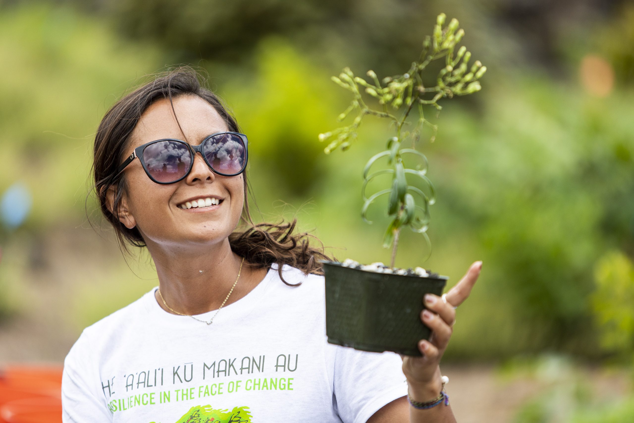 Photo of a girl wearing sunglasses holding a plant.