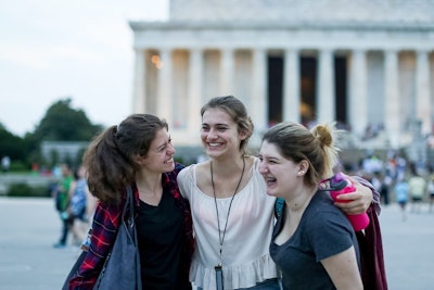 Three teen travelers laughing together while exploring a cultural landmark on a teen tour in the USA.