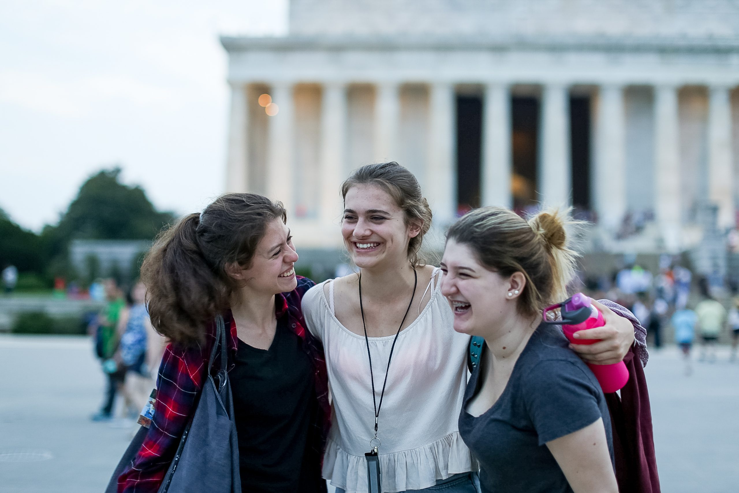 Three high school volunteer abroad students laughing together while exploring a cultural landmark overseas.