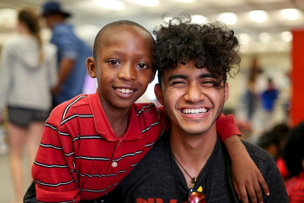 Teen volunteer abroad program participant smiling with a local child during a community service experience overseas.