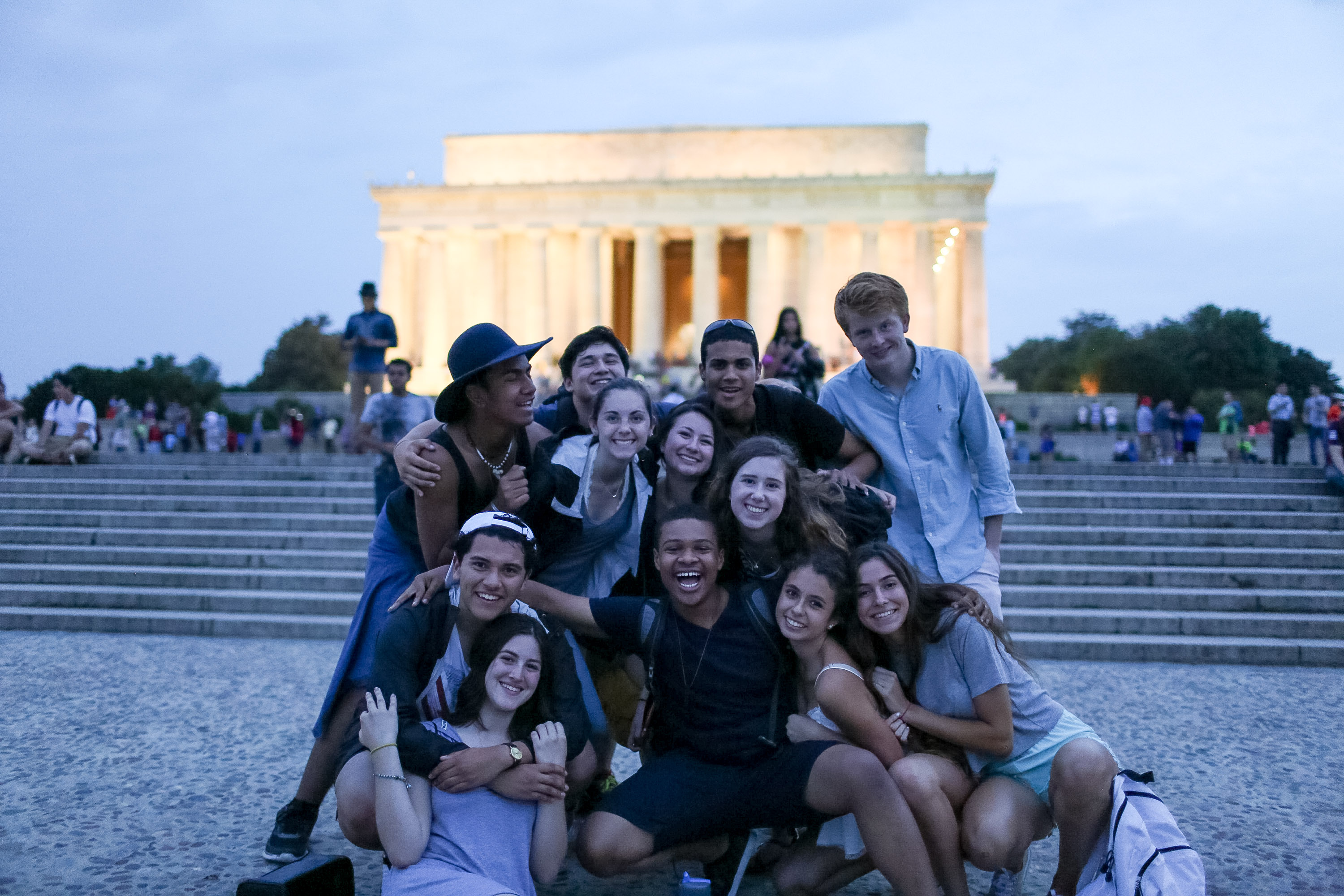 Students pose together at dusk in front of the Lincoln Memorial