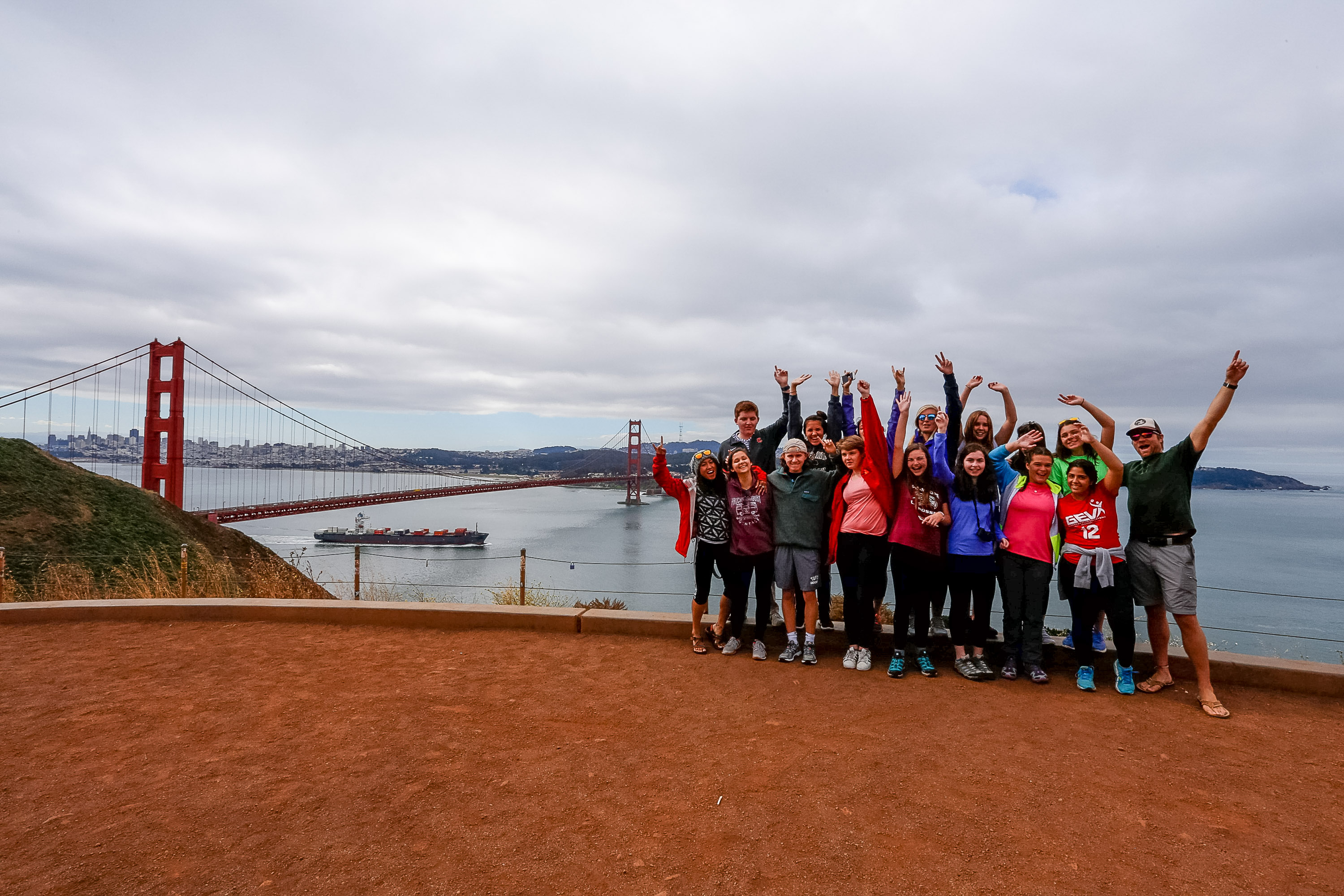 Students raise their arms overlooking the Golden Gate Bridge and bay