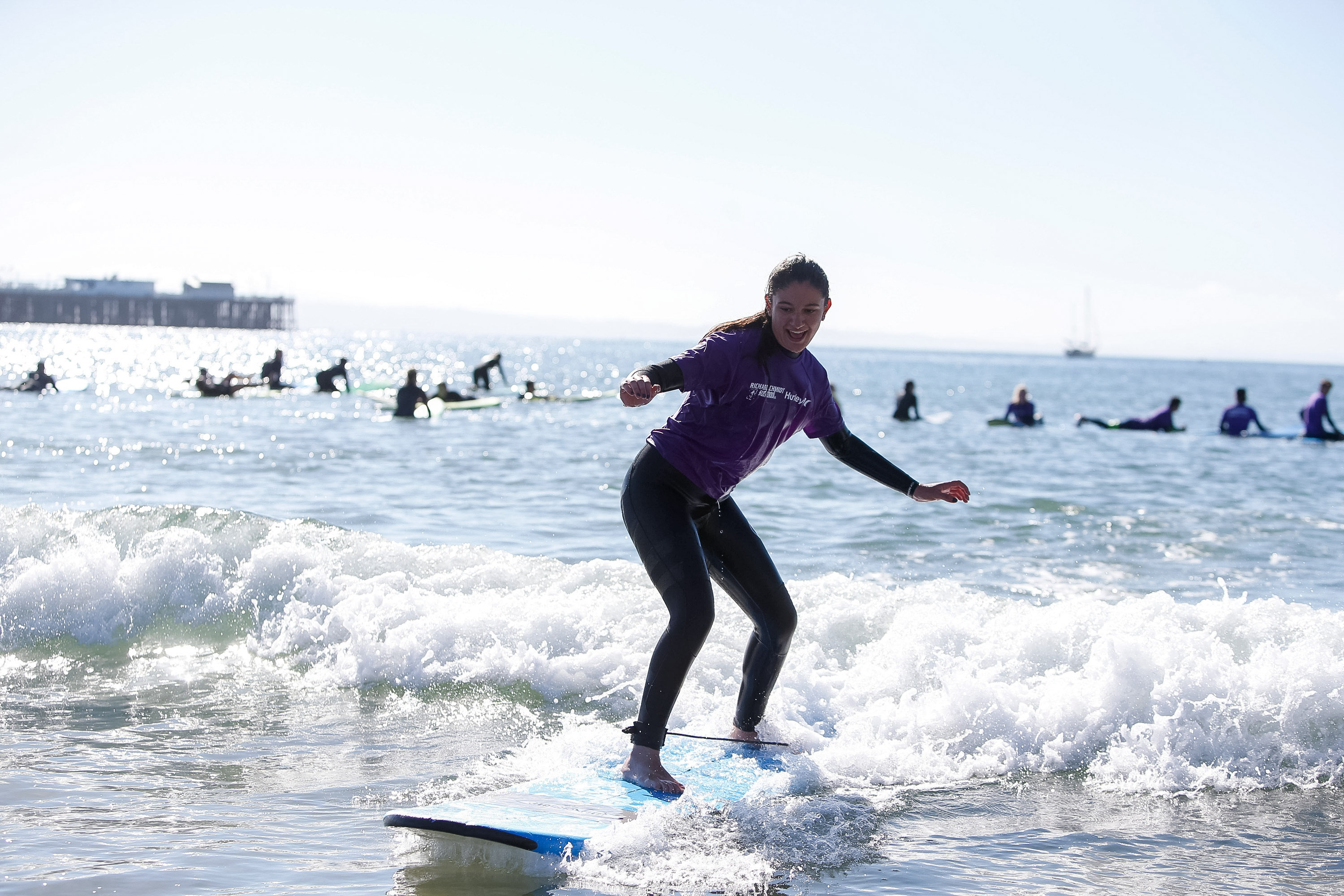 A student balances on a surfboard while riding a small wave in the United States
