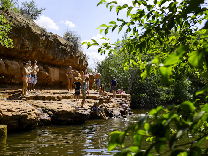 A green creek runs between red rock walls at the canyon floor.