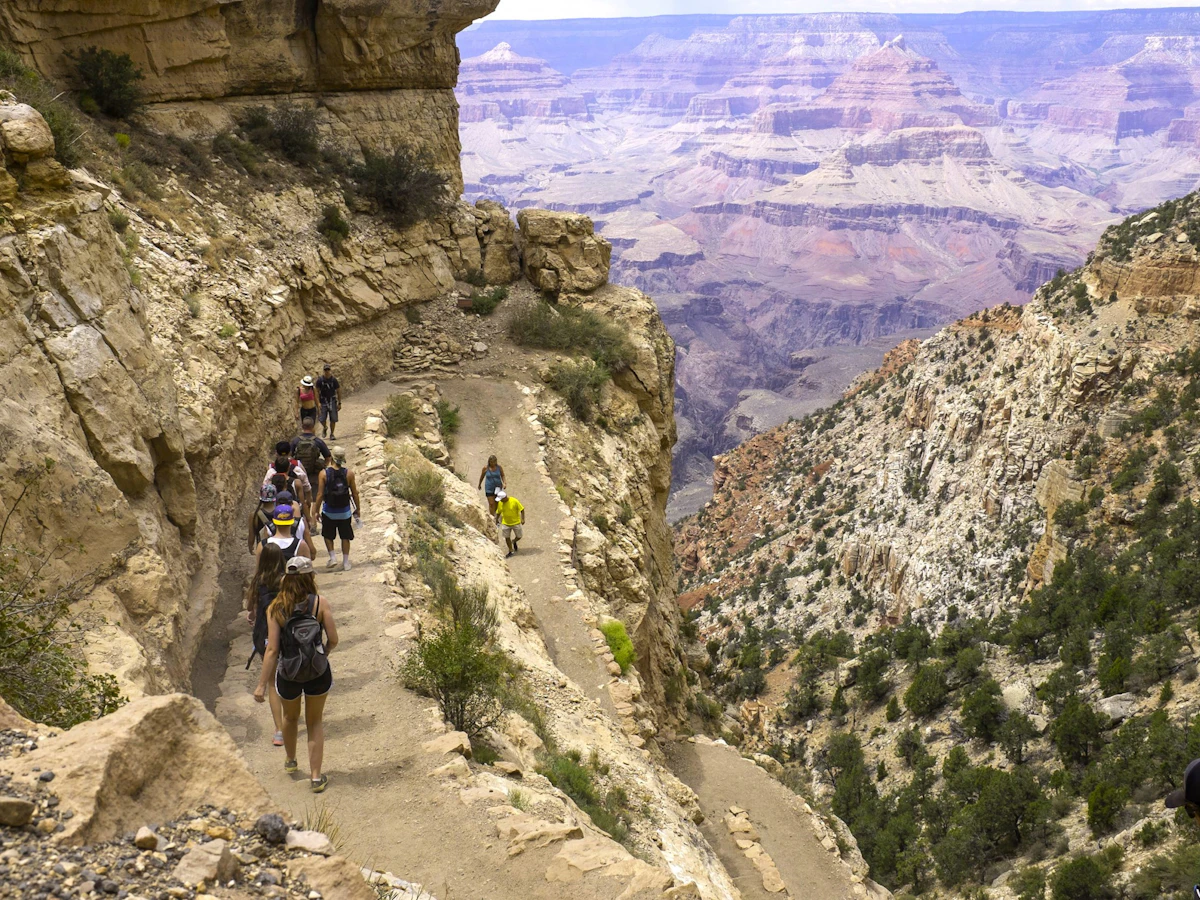 A school group descends a switchback trail below the canyon rim.