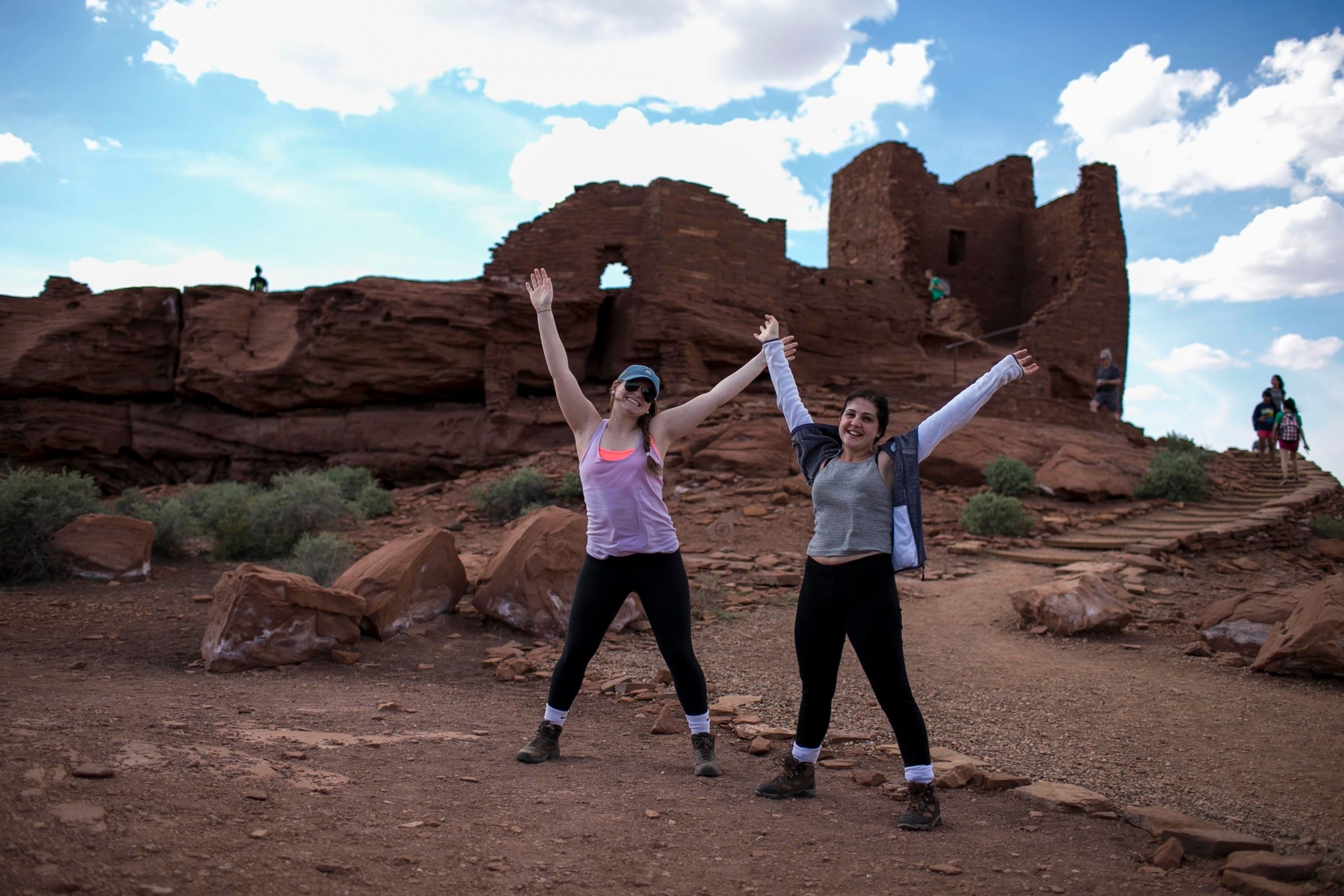 Students raise their arms in celebration near ancient stone ruins
