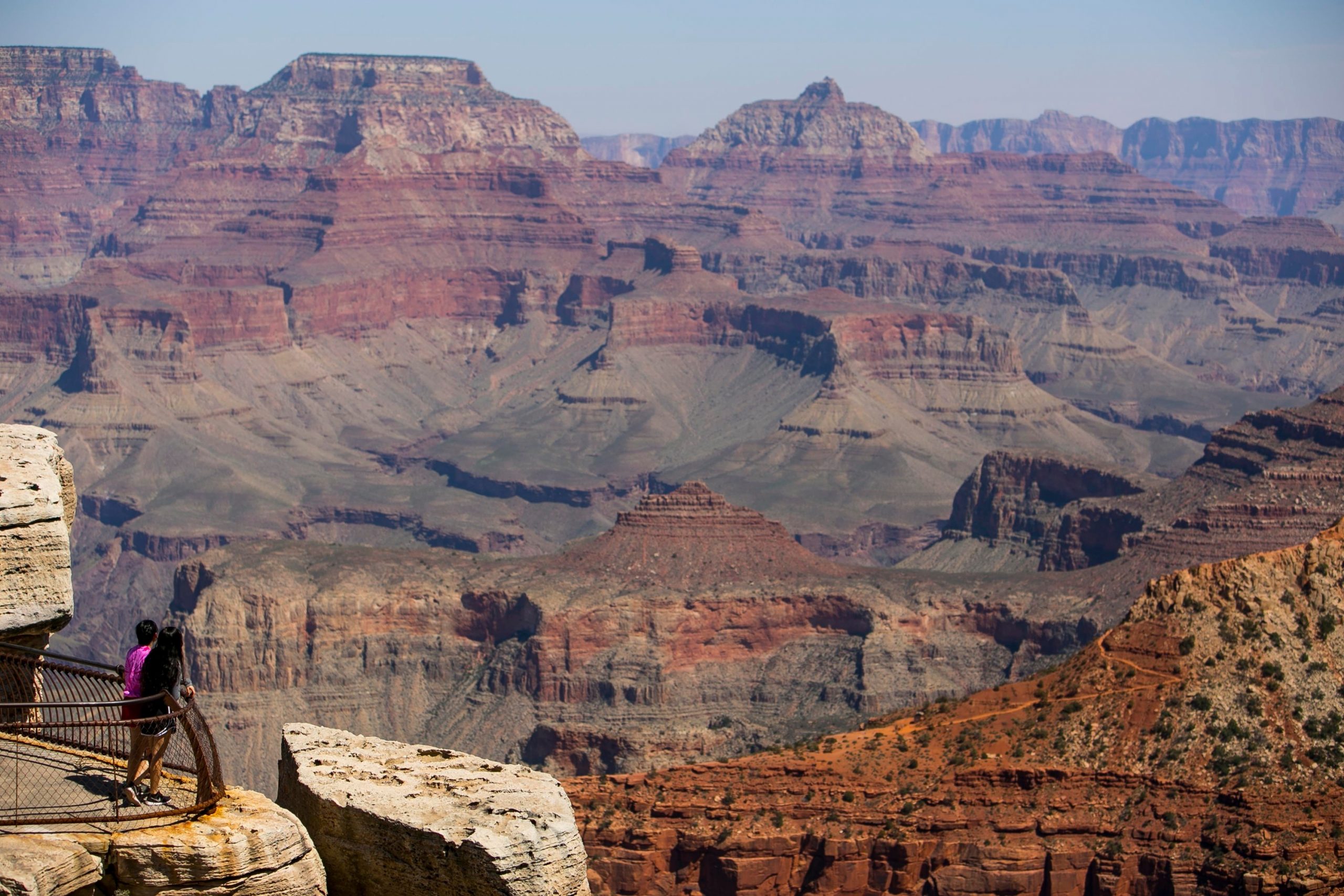 Students look out over the layered cliffs of the Grand Canyon from a rocky overlook