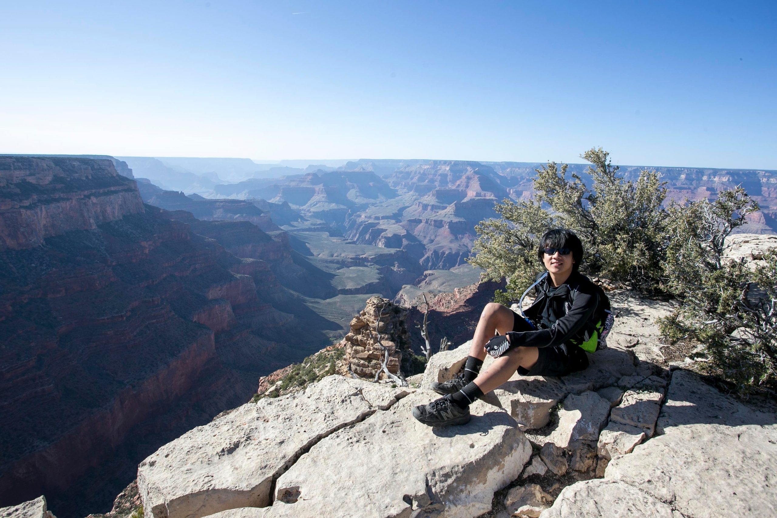 A student sits on a rock ledge overlooking the Grand Canyon
