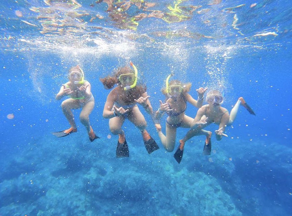 Students snorkeling together over coral reefs during a marine conservation volunteering program in Fiji.