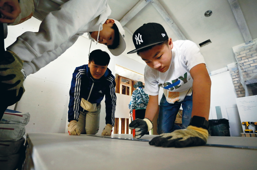 Students in work gloves building a frame on a Boston service project.