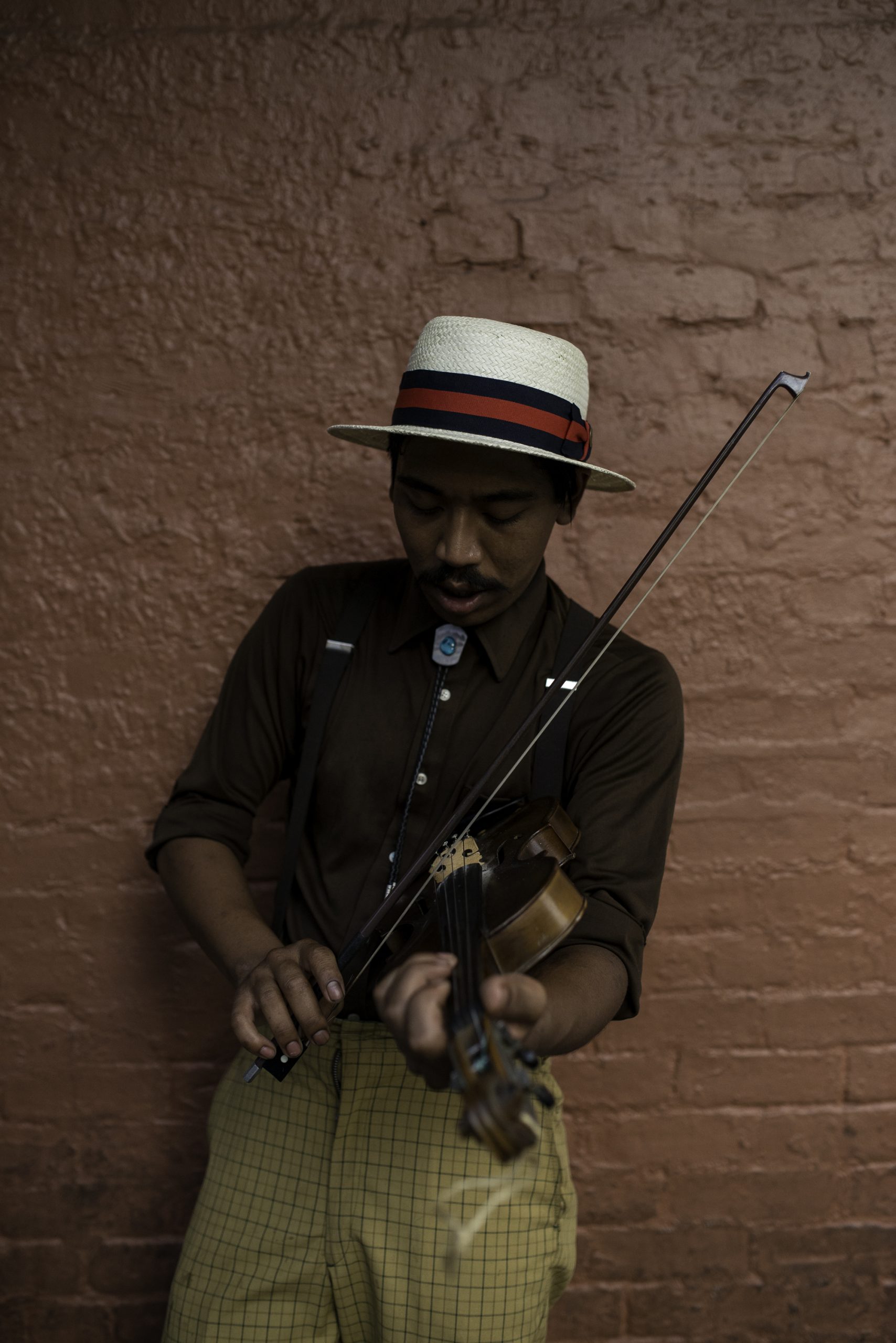 A musician in a straw hat plays violin on a New Orleans street.