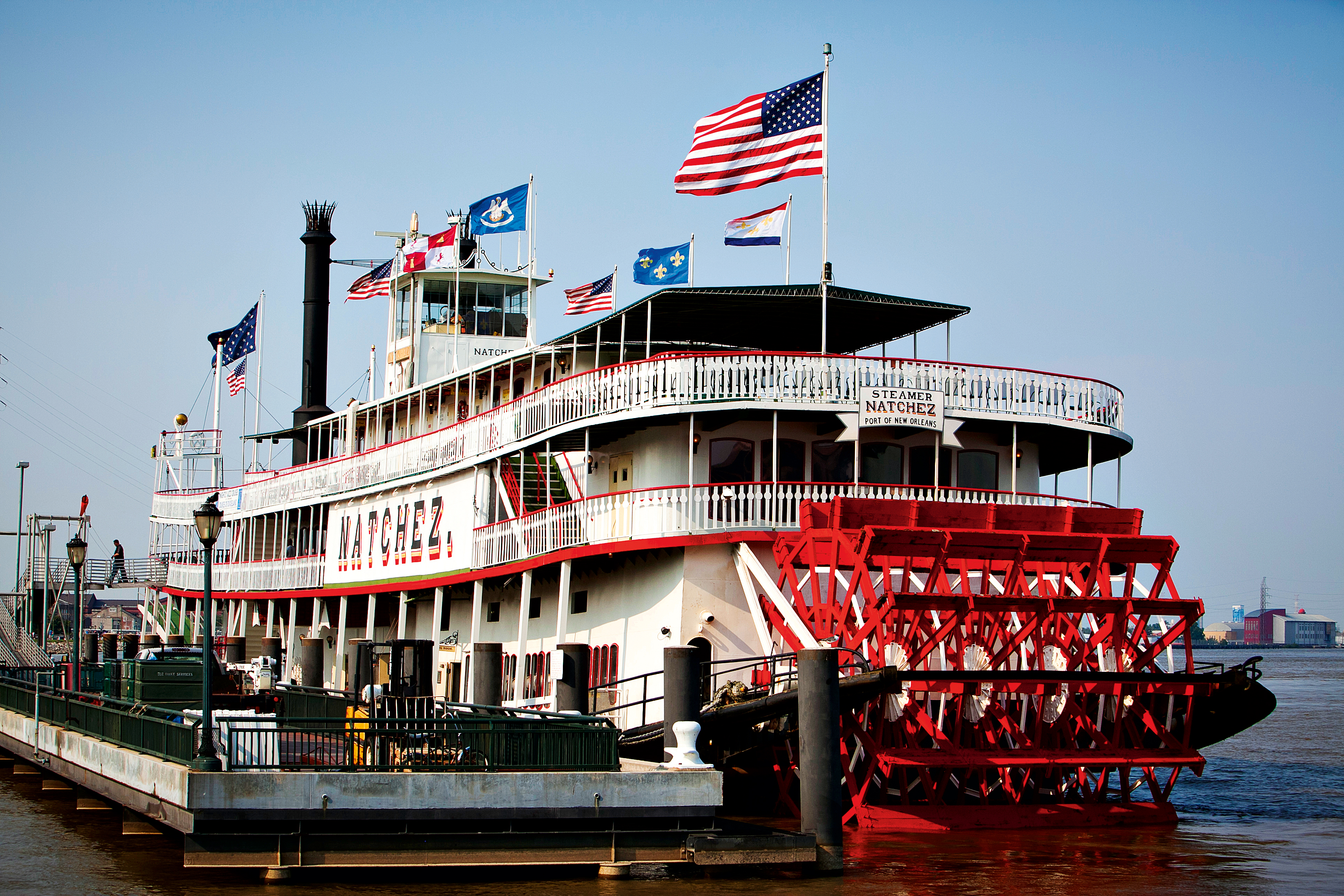 Large ferry with many flags in a dock in New Orleans.