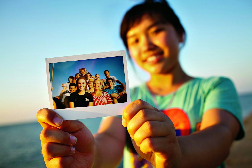 High school volunteer abroad student holding a group photo with fellow volunteers during an international service trip.