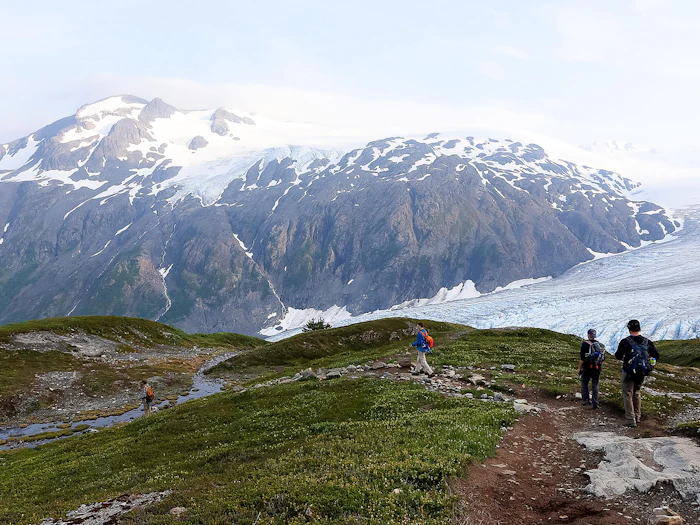 A trail crosses the tundra toward a glacier at the valley head.