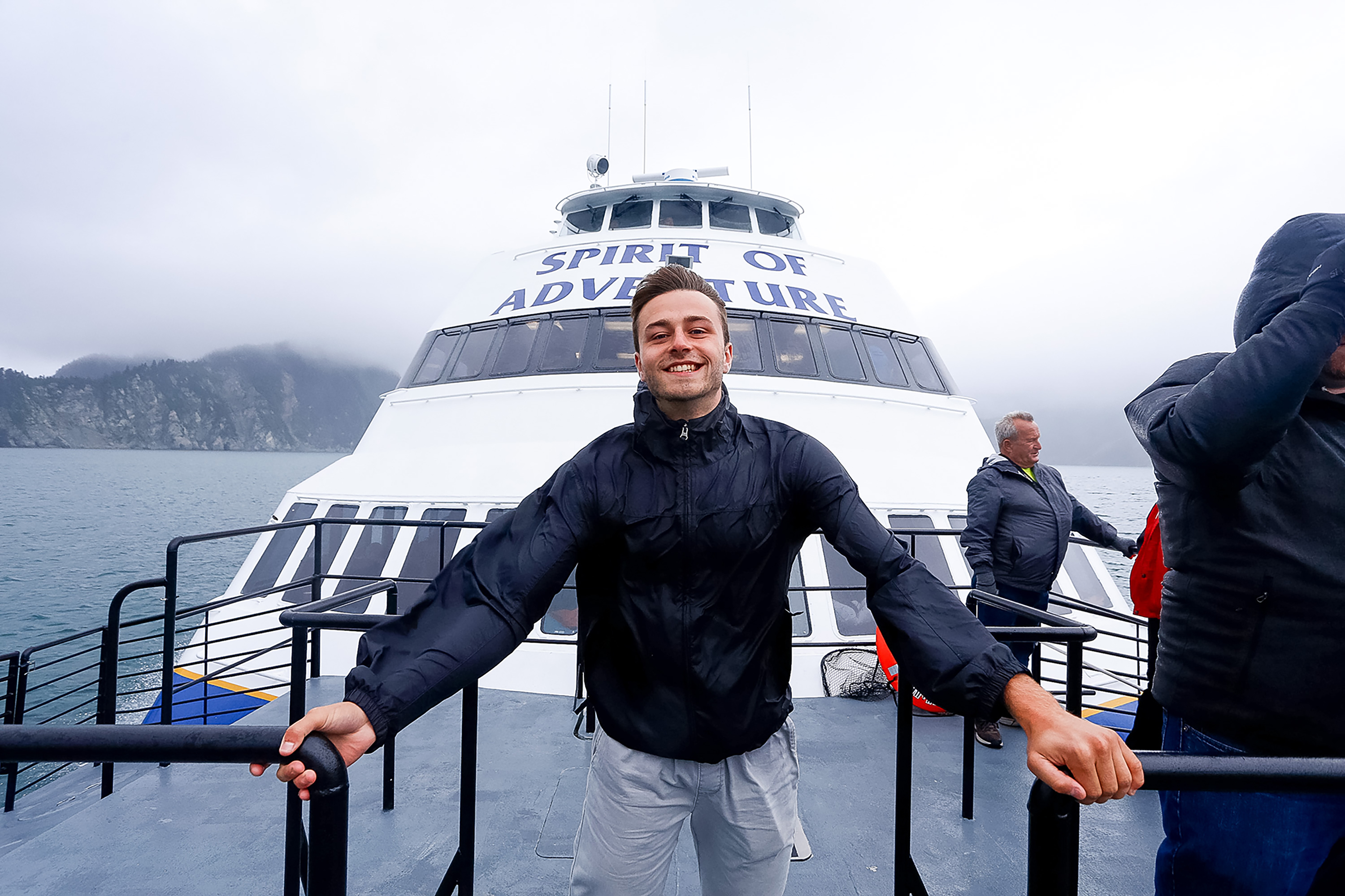 A student poses on deck aboard the Spirit of Adventure boat, cruising misty mountains in the United States