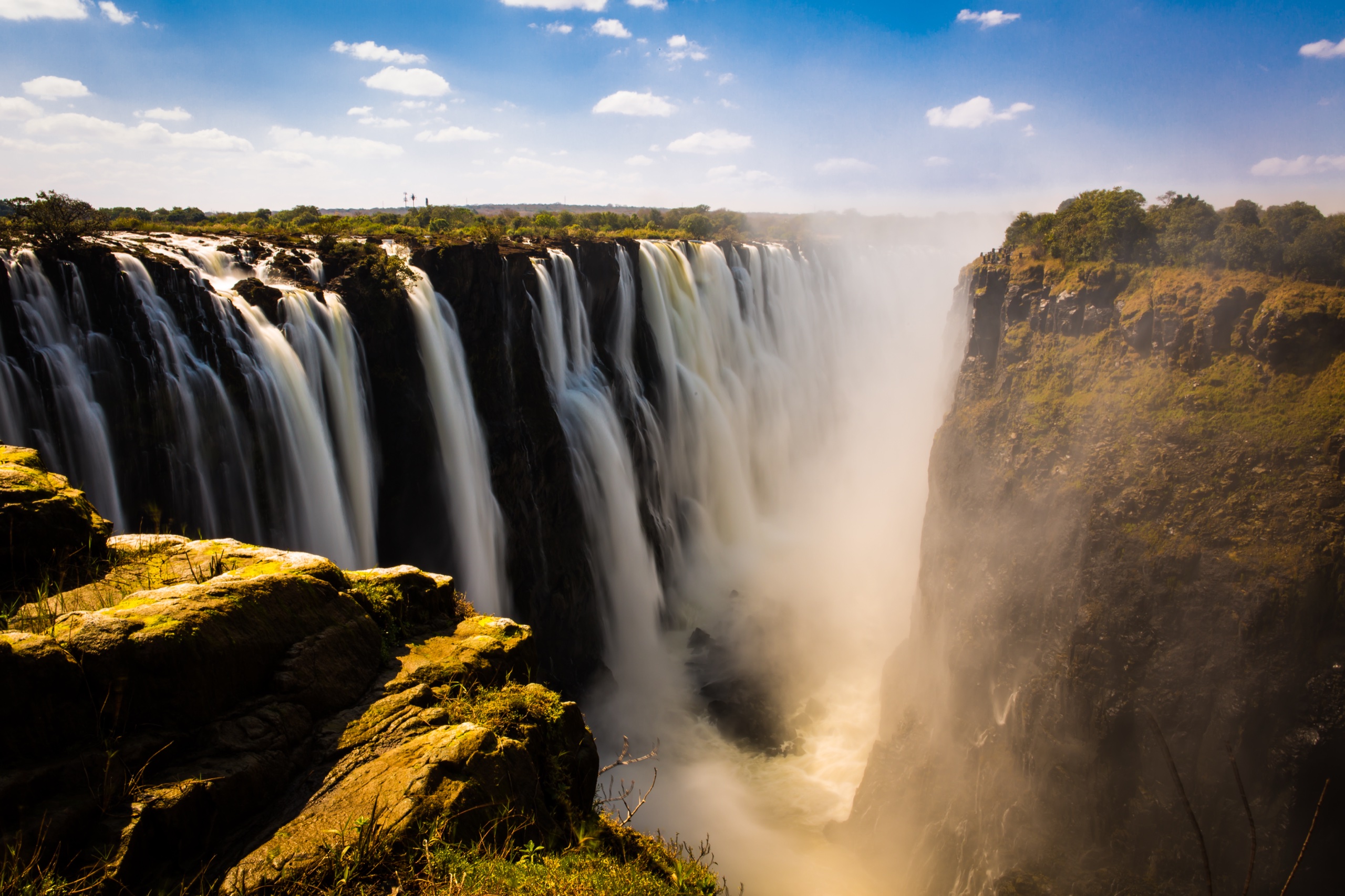 Victoria Falls, a stop on a school trip to Zimbabwe, pours into a deep misty gorge under a blue sky
