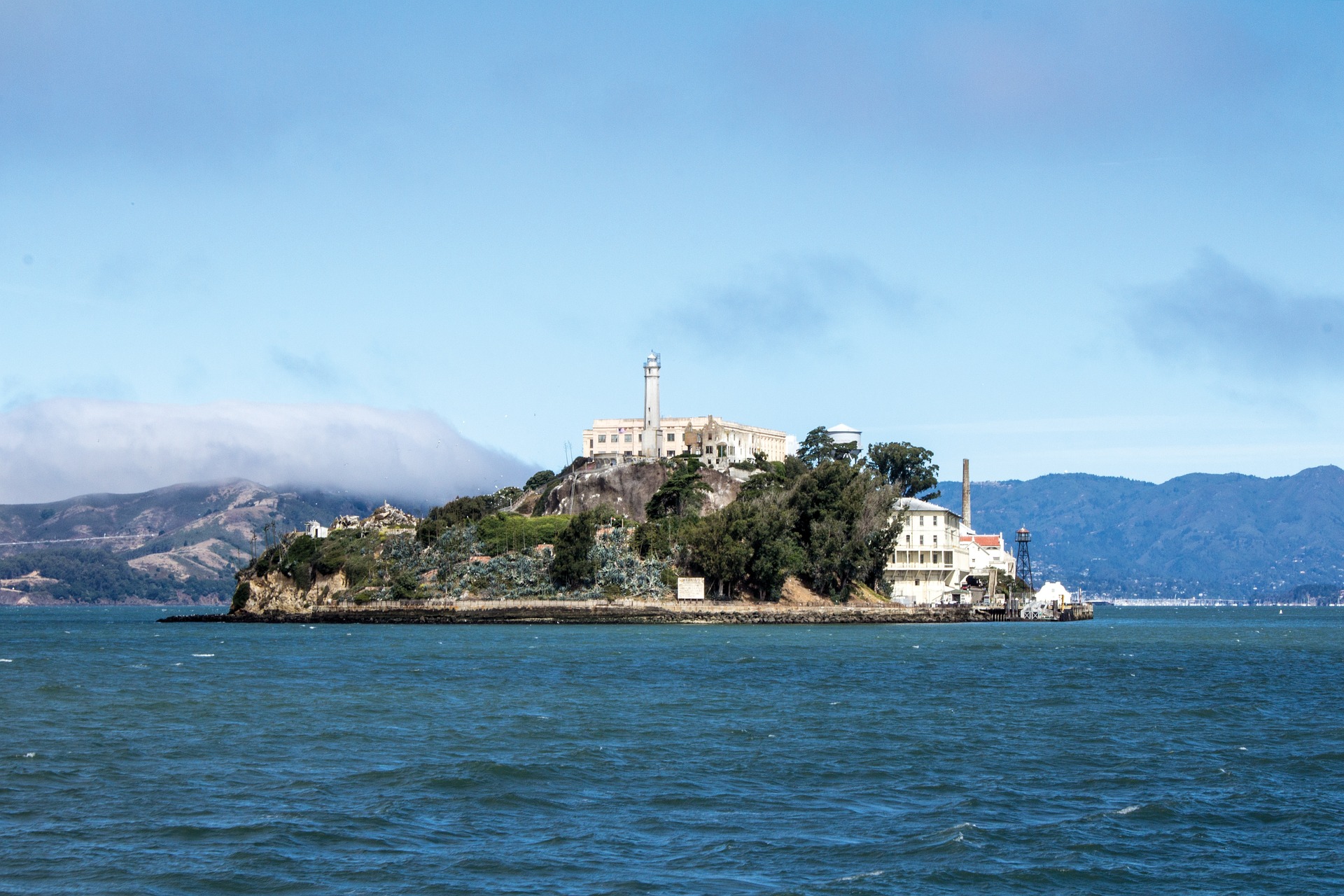 Alcatraz Island rises above San Francisco Bay with hills in the distance
