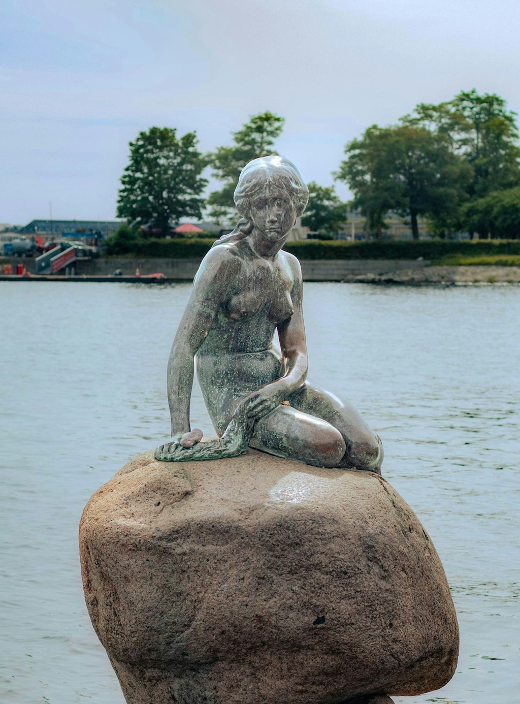 Bronze little Mermaid statue in Copenhagen on a rock.