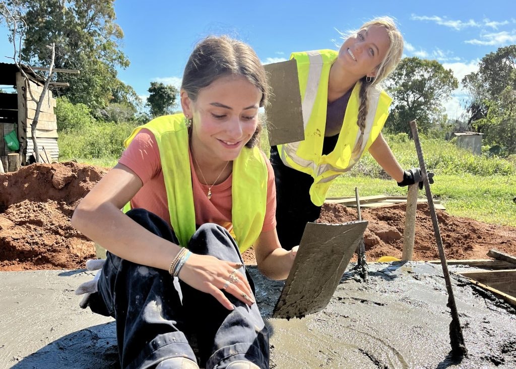 Two student volunteers working together on construction project.