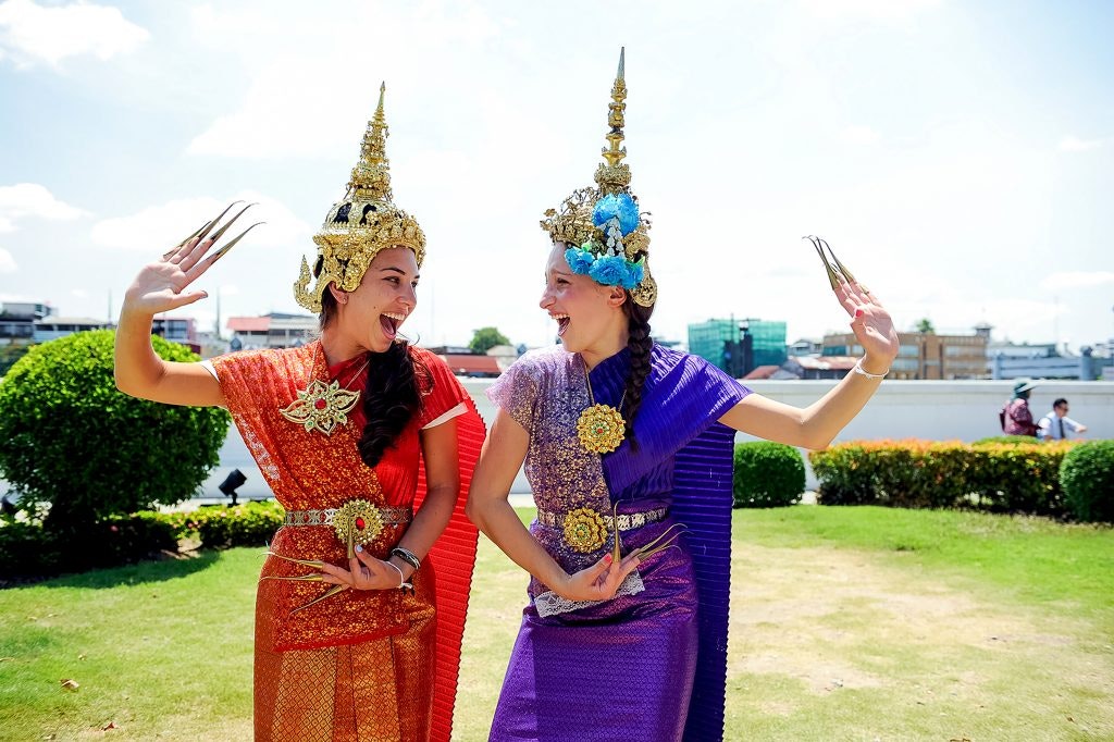 Two girls on a teen travel program dressed in traditional Thai outfits immerse themselves in local culture.