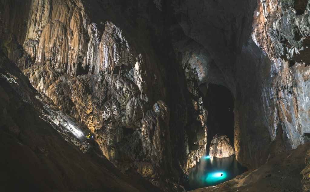 Majestic interior of Son Doong Cave in Vietnam with illuminated sections showcasing its vastness.