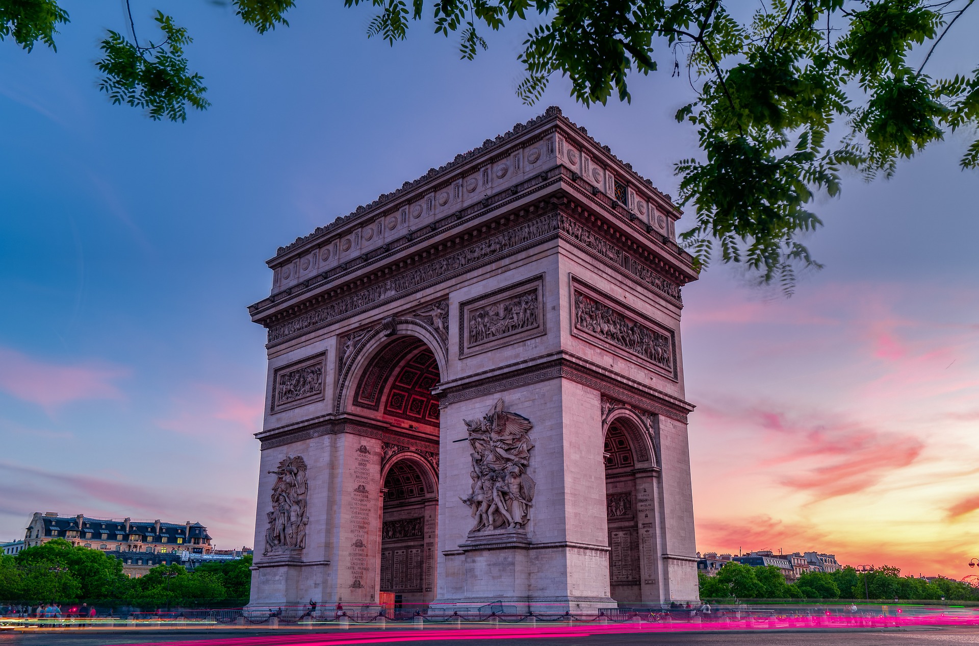The Arc de Triomphe rises against a colorful sunset sky in Paris