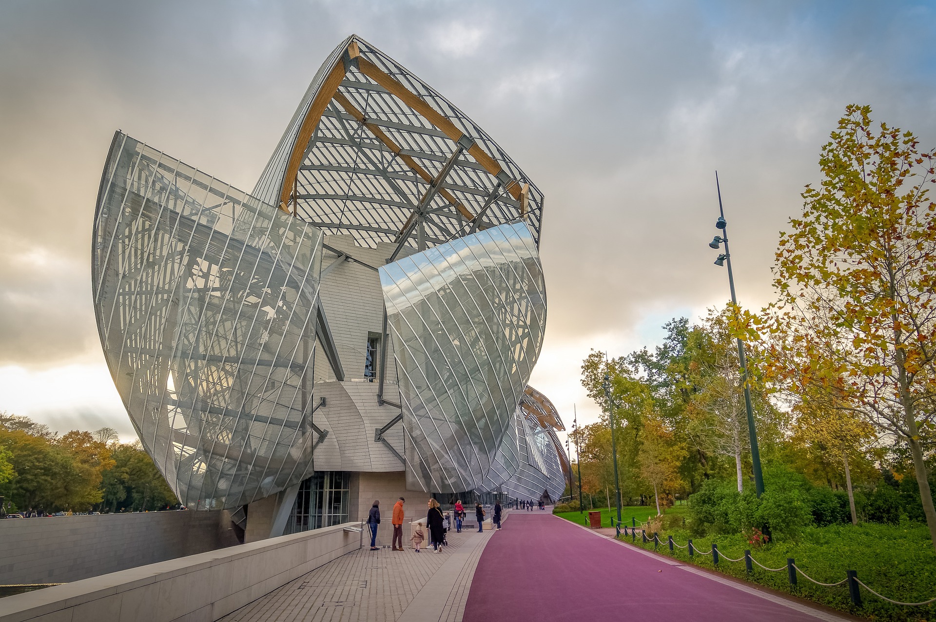 Visitors walk near the curved glass architecture of the Fondation Louis Vuitton in Paris