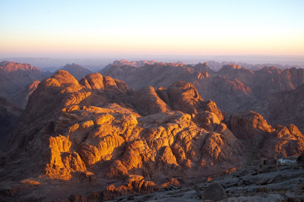 The rugged peaks of Mount Sinai glow with golden hues as the sun rises over the dramatic desert landscape. fun facts about egypt