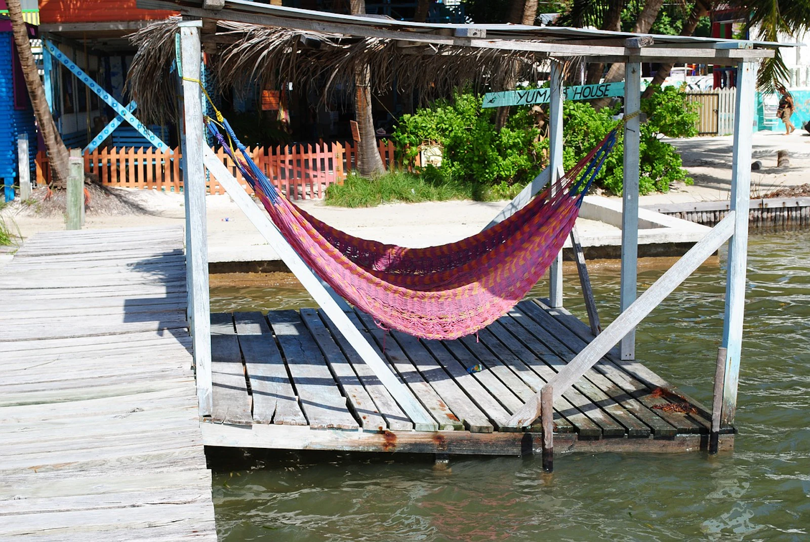 A hammock hangs over the water on a wooden dock in Belize