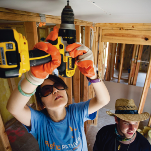 best service trips for teens a rustic pathways girl drilling into the roof wearing big sunglasses