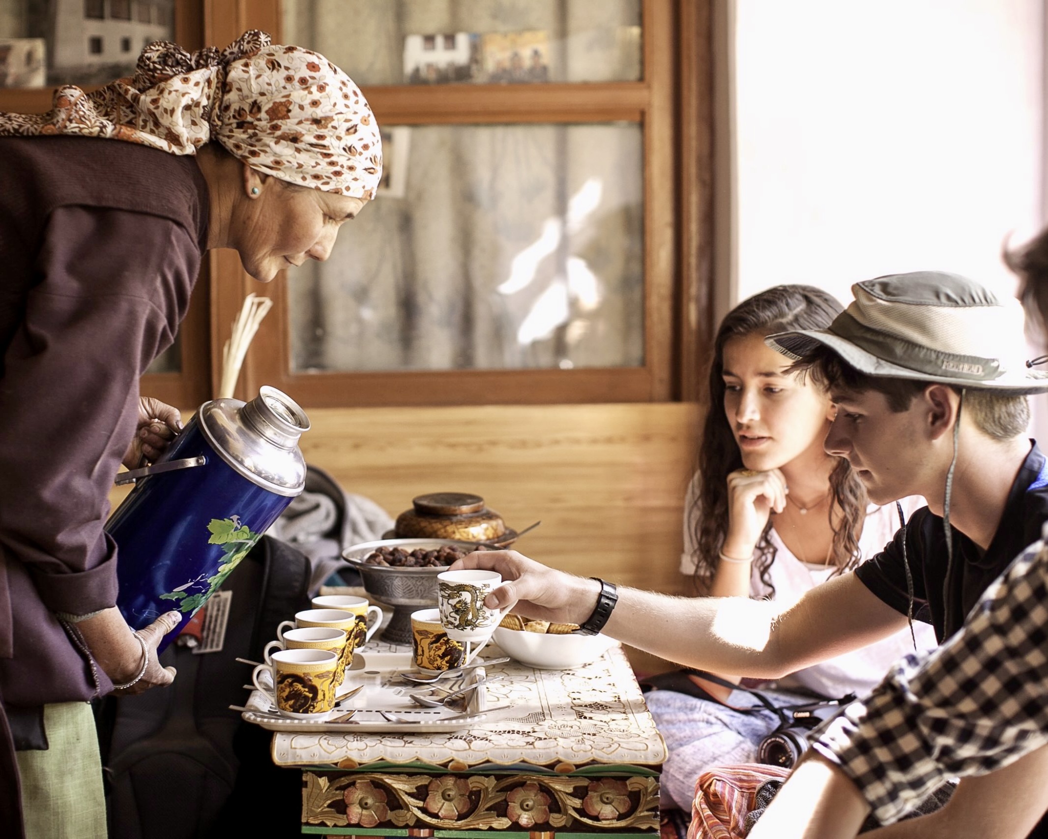 A host pours tea for teen travelers during a Himalayan homestay on a Rustic Pathways cultural immersion program