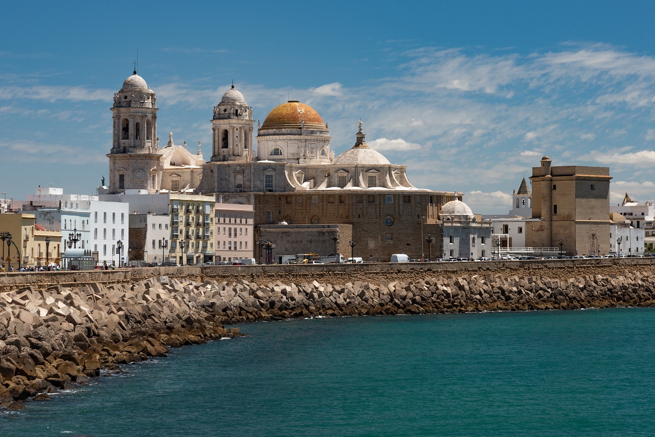 On a school trip, students pause below Cadiz Cathedral's domed towers, which rise above a stone breakwater along the coast