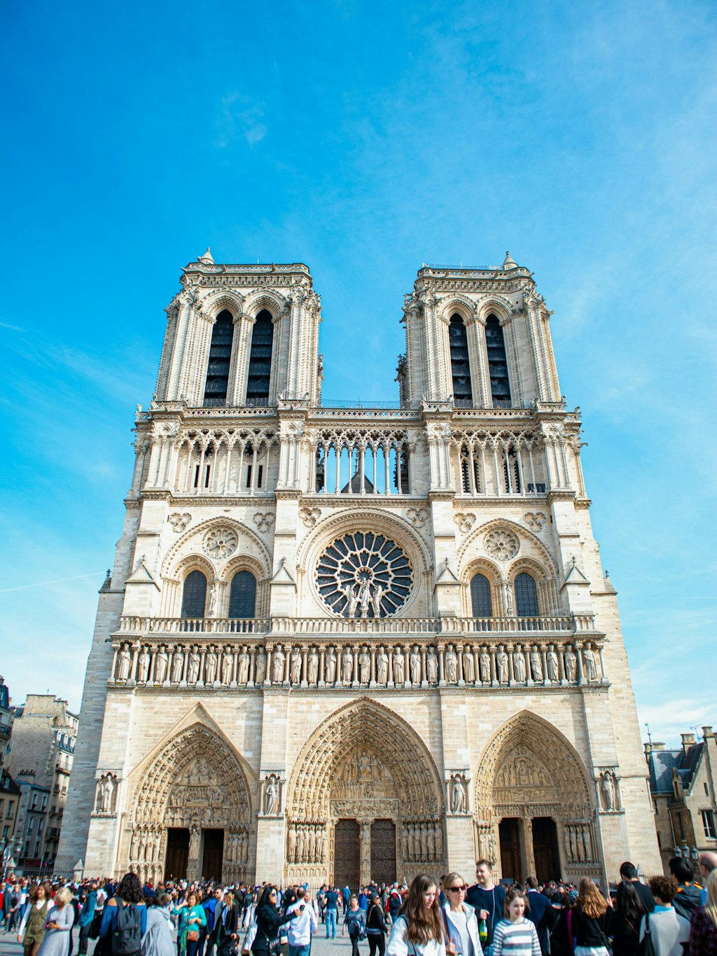Notre-Dame Cathedral stands tall in the sun under a clear blue sky, its beautiful Gothic details shining brightly.