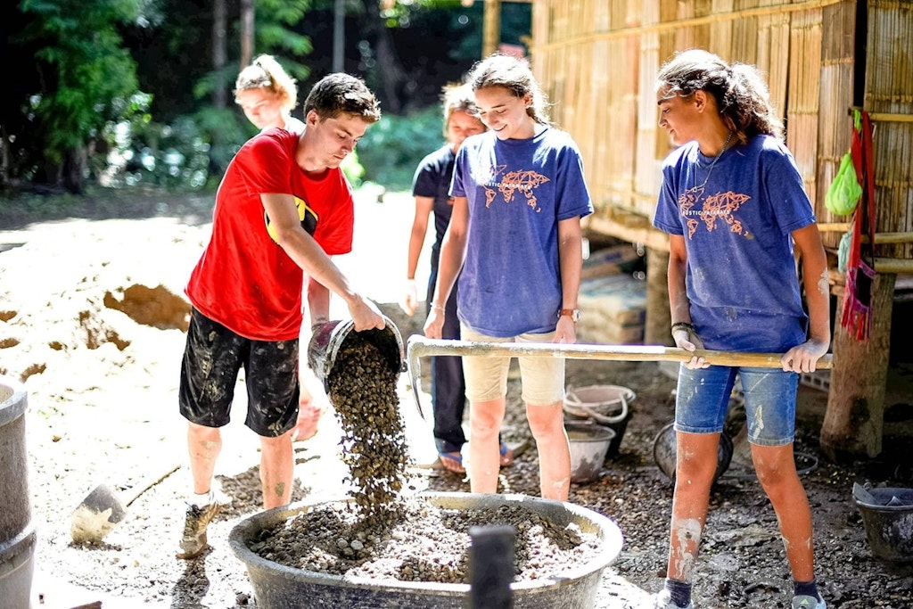 College volunteer abroad participants mixing materials and building structures during a hands-on community service project.