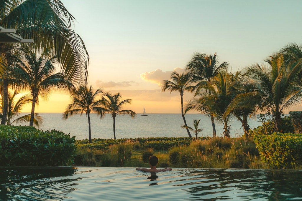 A woman stares at the horizon from the comfort of an outdoor swimming pool.
