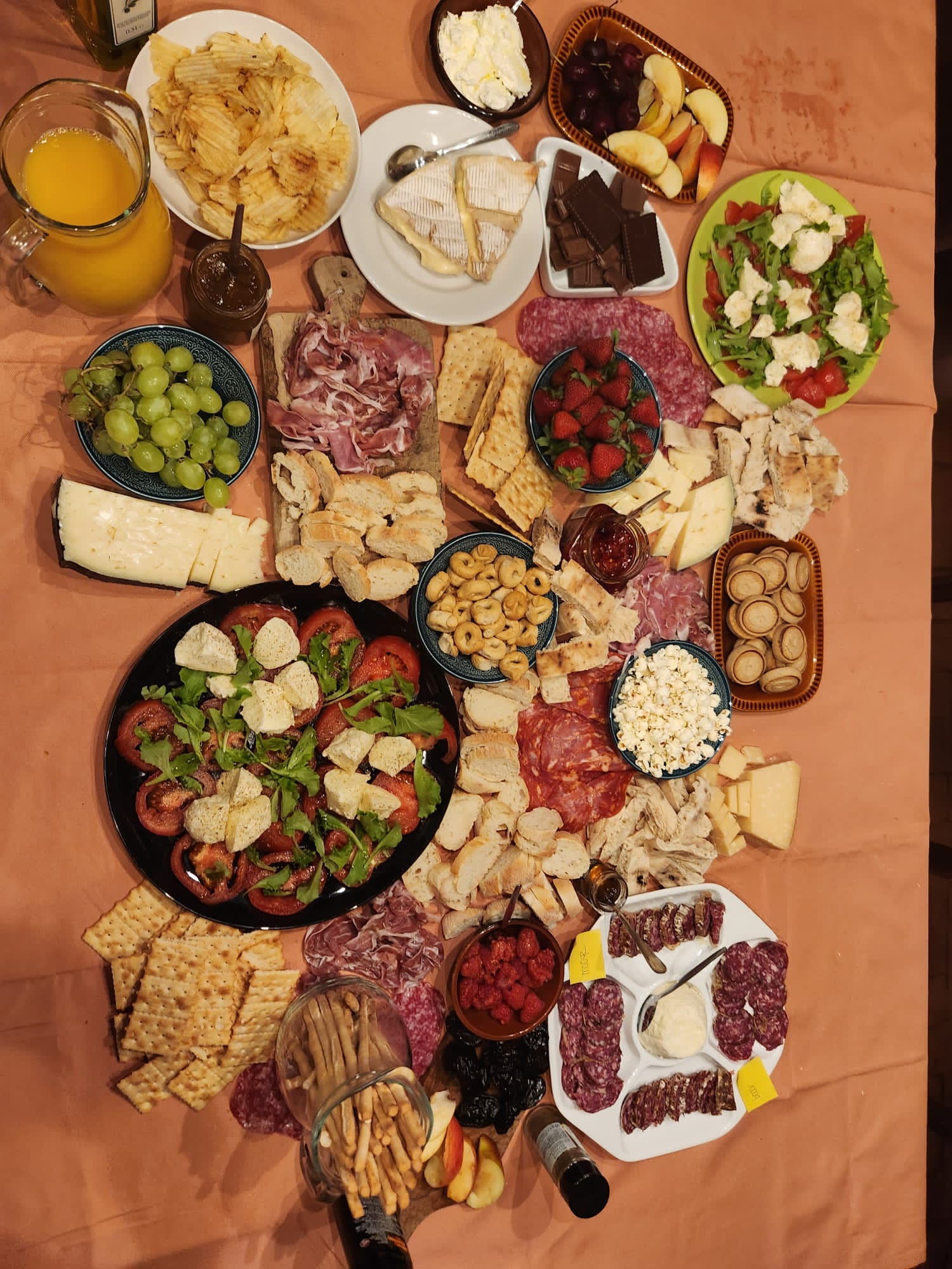 Students gather around a table spread with Italian cheeses, cured meats, fruit, salads and crackers