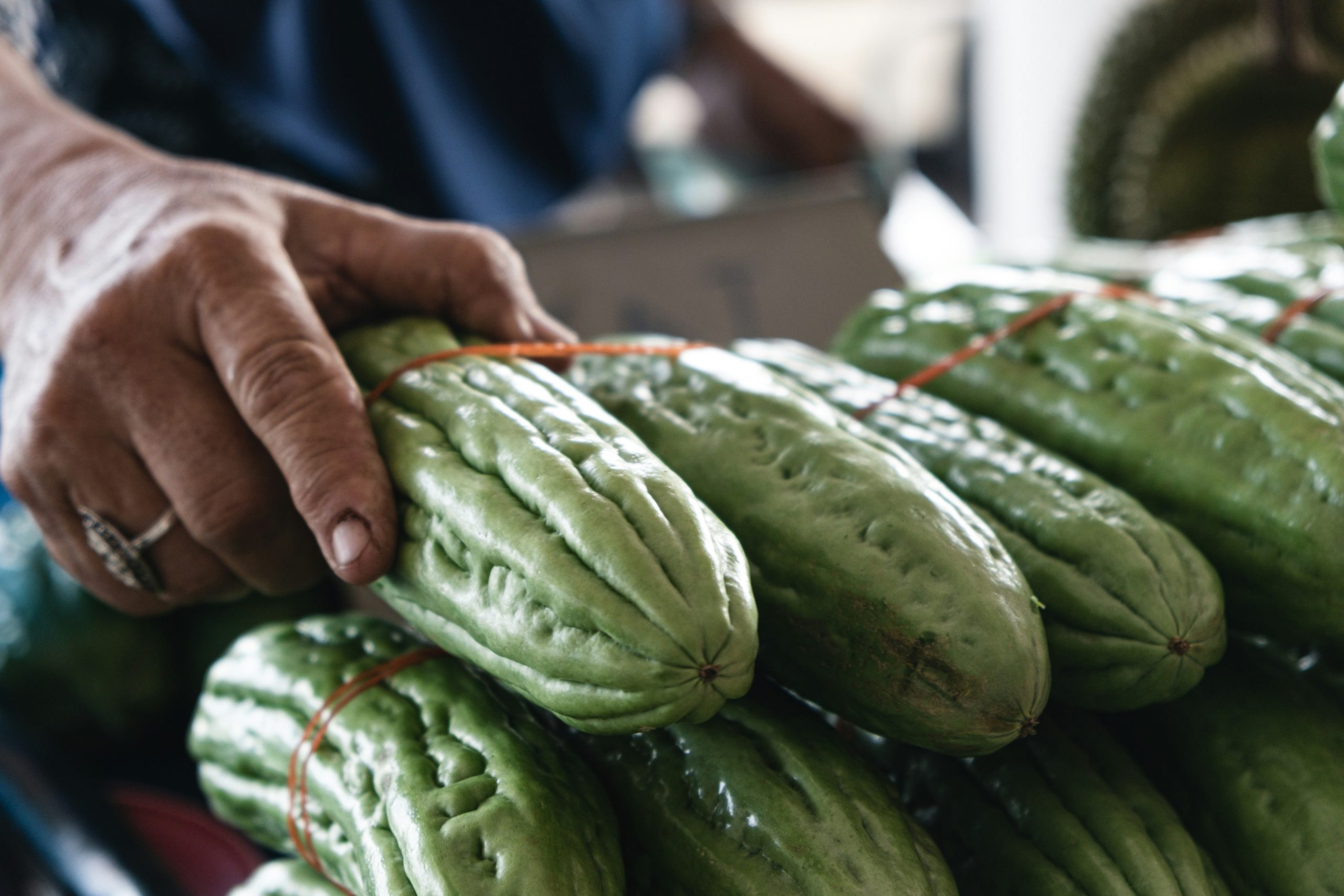 Person holding fresh green vegetables at a market