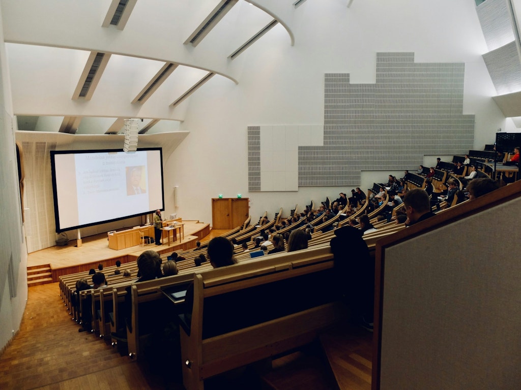 Students attending a lecture in a modern university hall, representing higher education and how travel experience enhances college applications and academic essays.