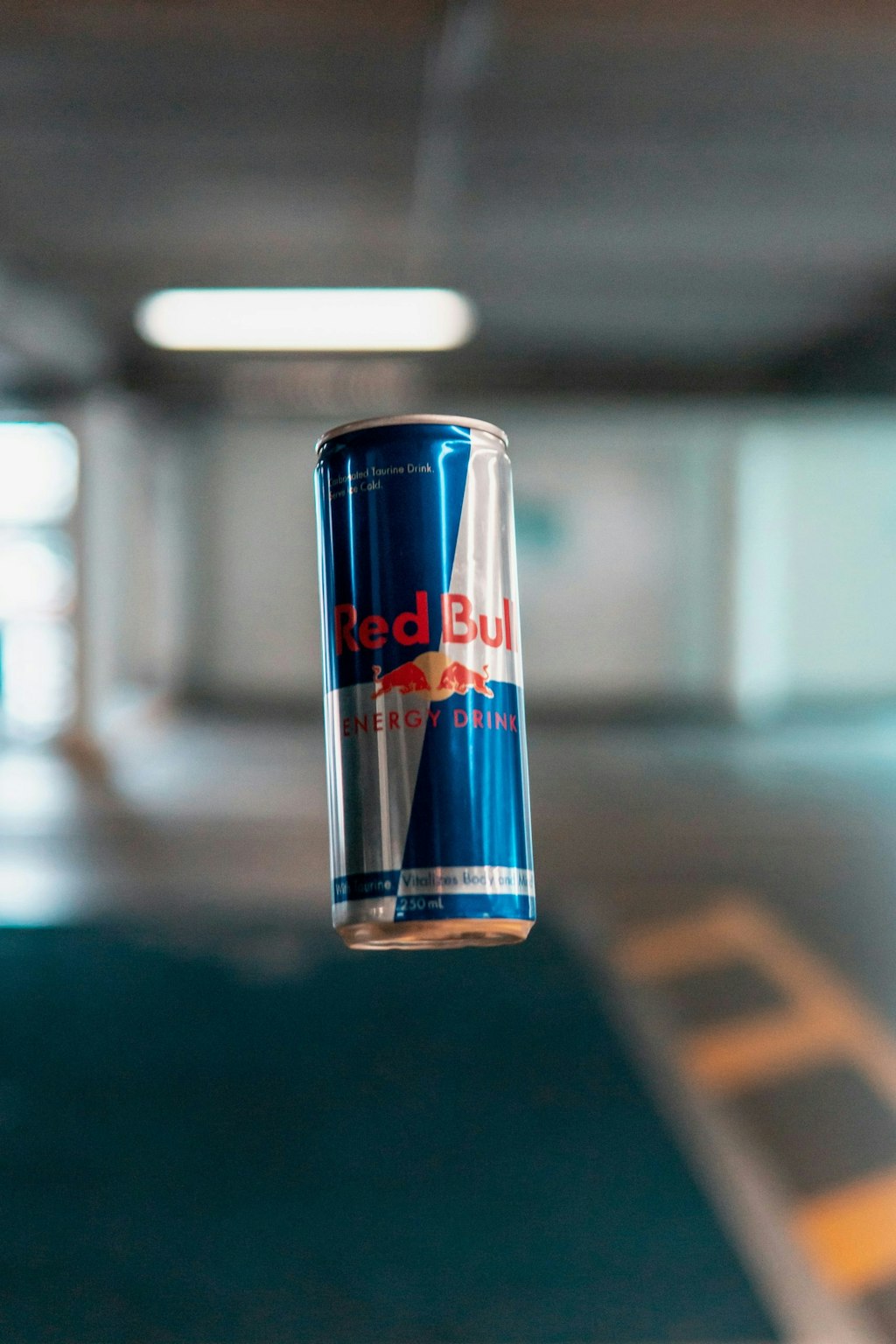A Red Bull can soars through the air, its blue and silver design catching the light.