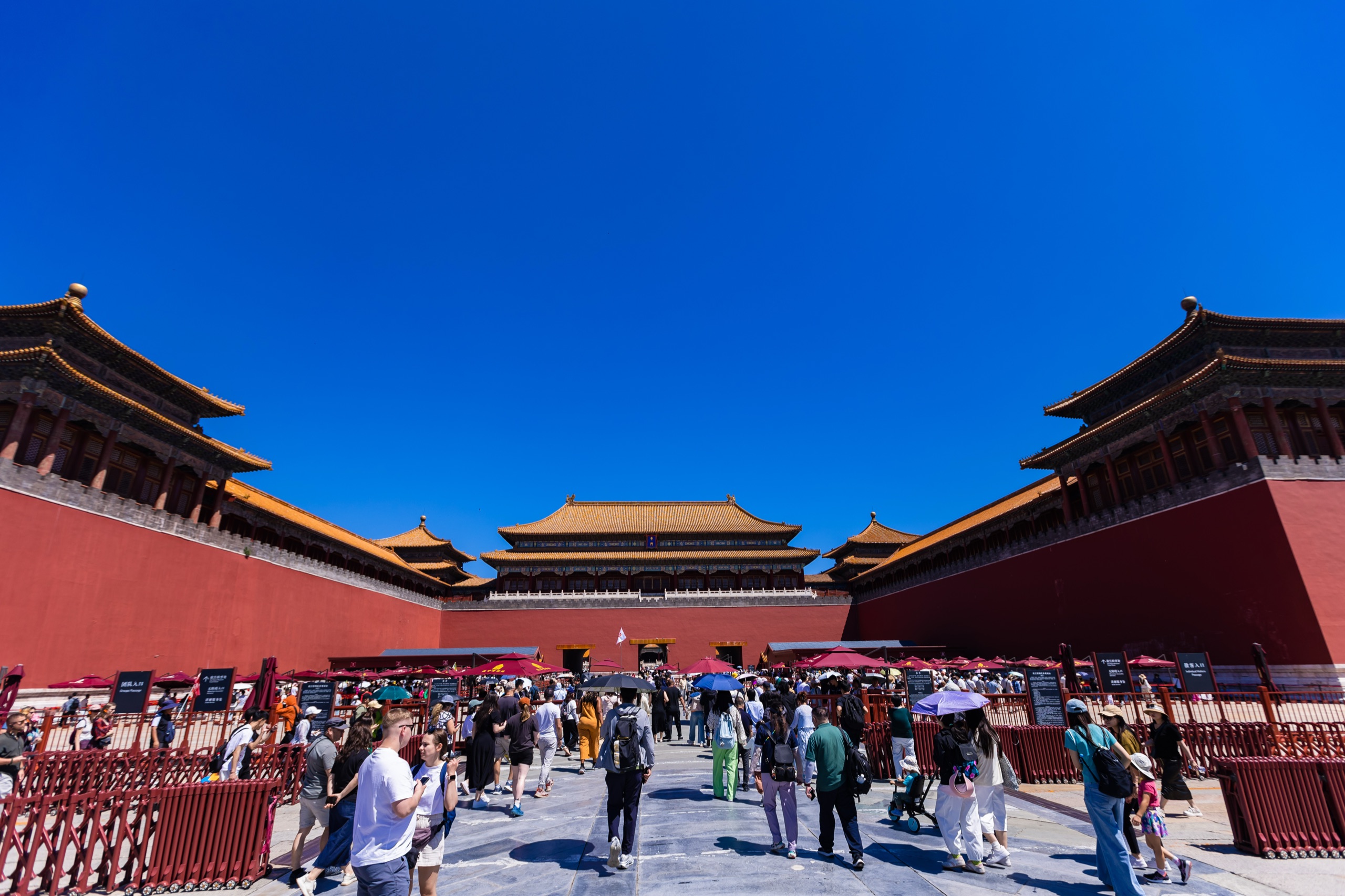Visitors in China gather beneath red walls and golden rooftops in the Forbidden City courtyard